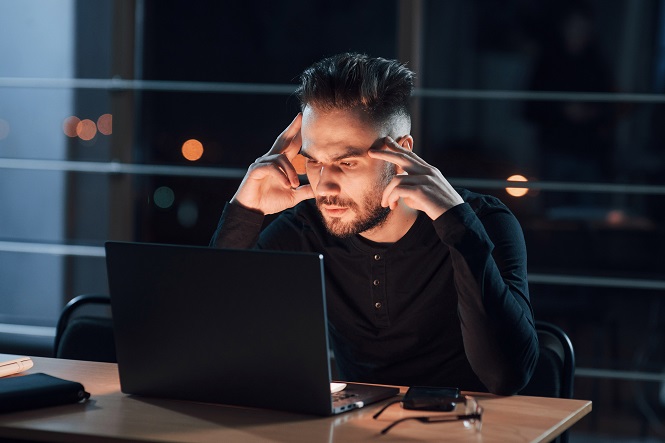 Tired look. Stylish young businessman on computer